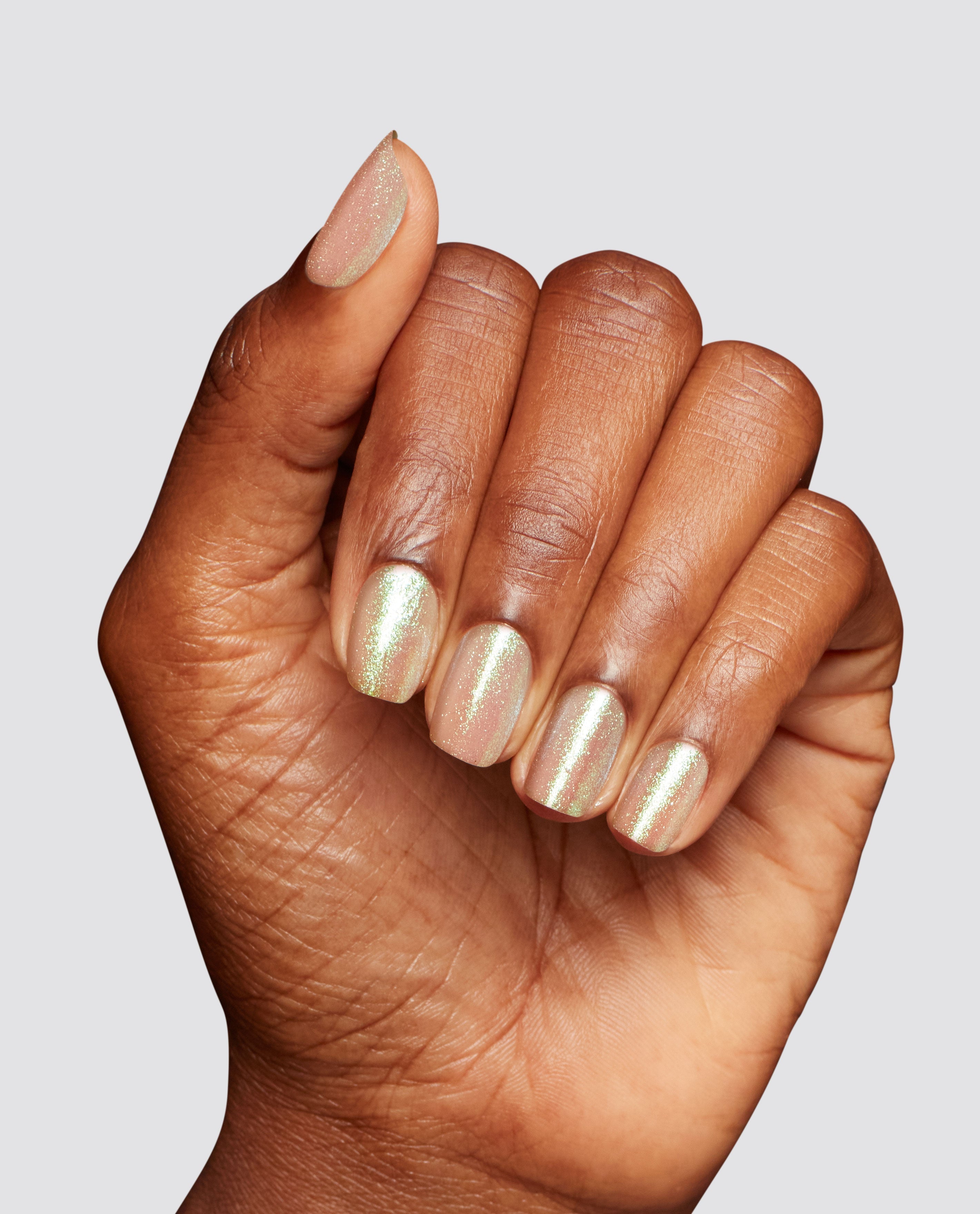 Hand shows short, neatly manicured nails painted with OPI MarshmelloOo So Sweet Infinite Shine, a soft pink nail polish gift set shade with fine iridescent shimmer against a clean light gray background.