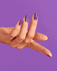 Hand with long nails painted in Medi-take It All In purple OPI nail polish flexes against a solid violet background, highlighting the glossy nail lacquer color and smooth finish for a bold manicure look.