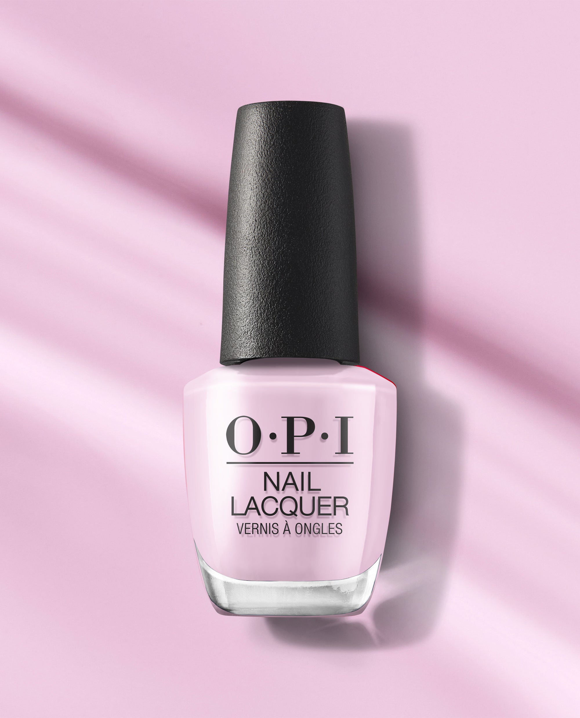 OPI Mod About Me nail lacquer bottle in soft pastel pink with a black textured cap, standing on a pink background with gentle shadows.
