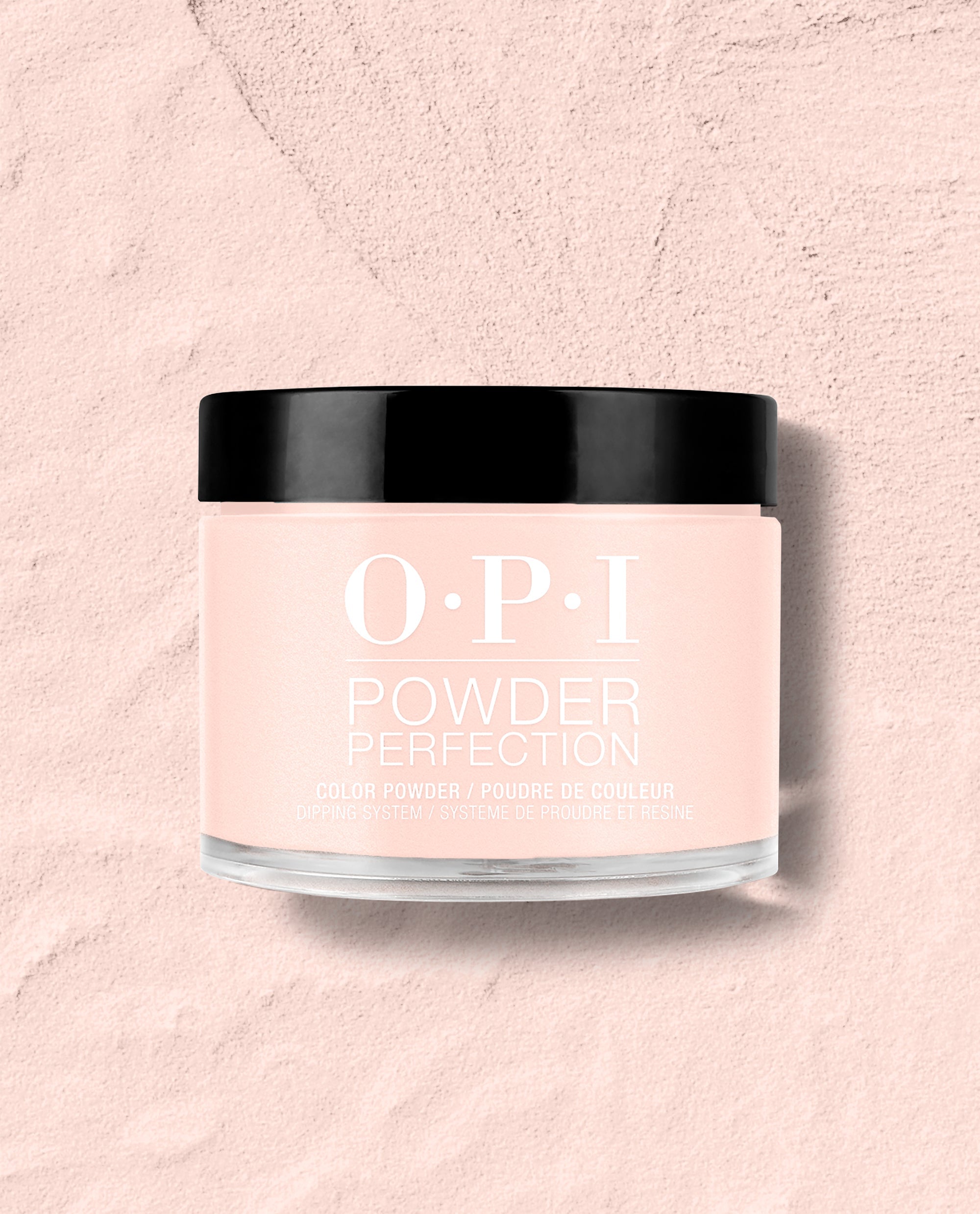 OPI Powder Perfection Mod About You Pastel dipping powder jar with a glossy black lid sits on a pale pink textured surface, showcasing a soft pink shade for fall nail colors.
