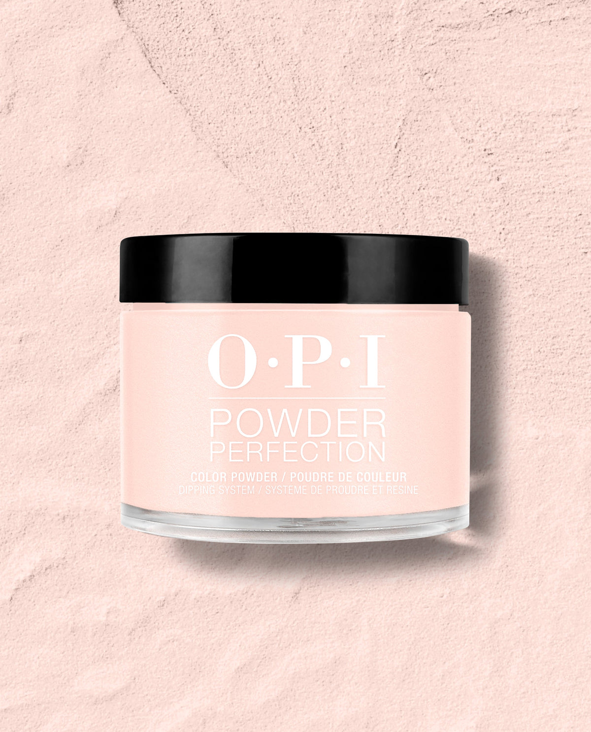 OPI Powder Perfection Mod About You Pastel dipping powder jar with a glossy black lid sits on a pale pink textured surface, showcasing a soft pink shade for fall nail colors.