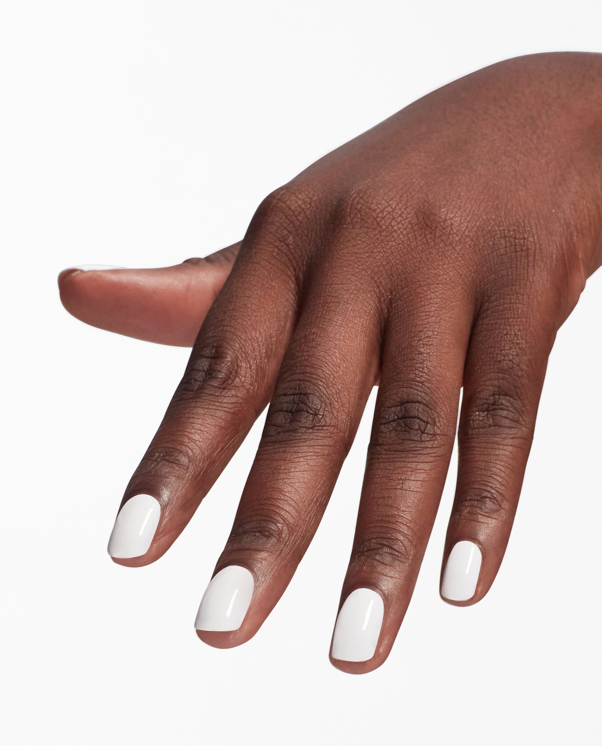 Hand modeling glossy white nails with OPI Nail Envy Alpine Snow nail strengthener, a trending treatment for a clean, opaque manicure on a plain white background.