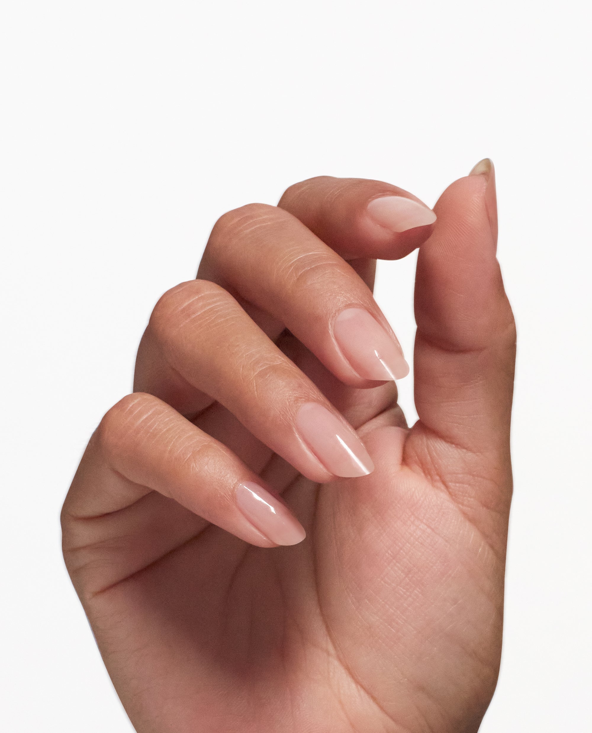 Hand with naturally long, glossy nude nails shows the strengthening results of OPI Nail Envy® Nail Strengthener treatment against a clean white background, ideal for marketing an OPI nail polish gift set in the US.
