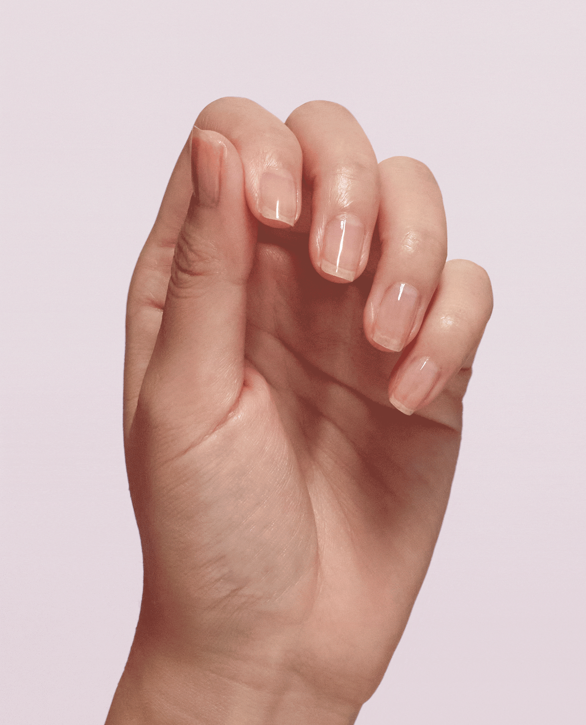 Hand shows natural nails transforming from bare to a glossy sheer pink finish, demonstrating Nail Envy® Pink To Envy Nail Strengthener treatment by OPI, ideal as a nail polish gift set for stronger, healthier-looking nails.