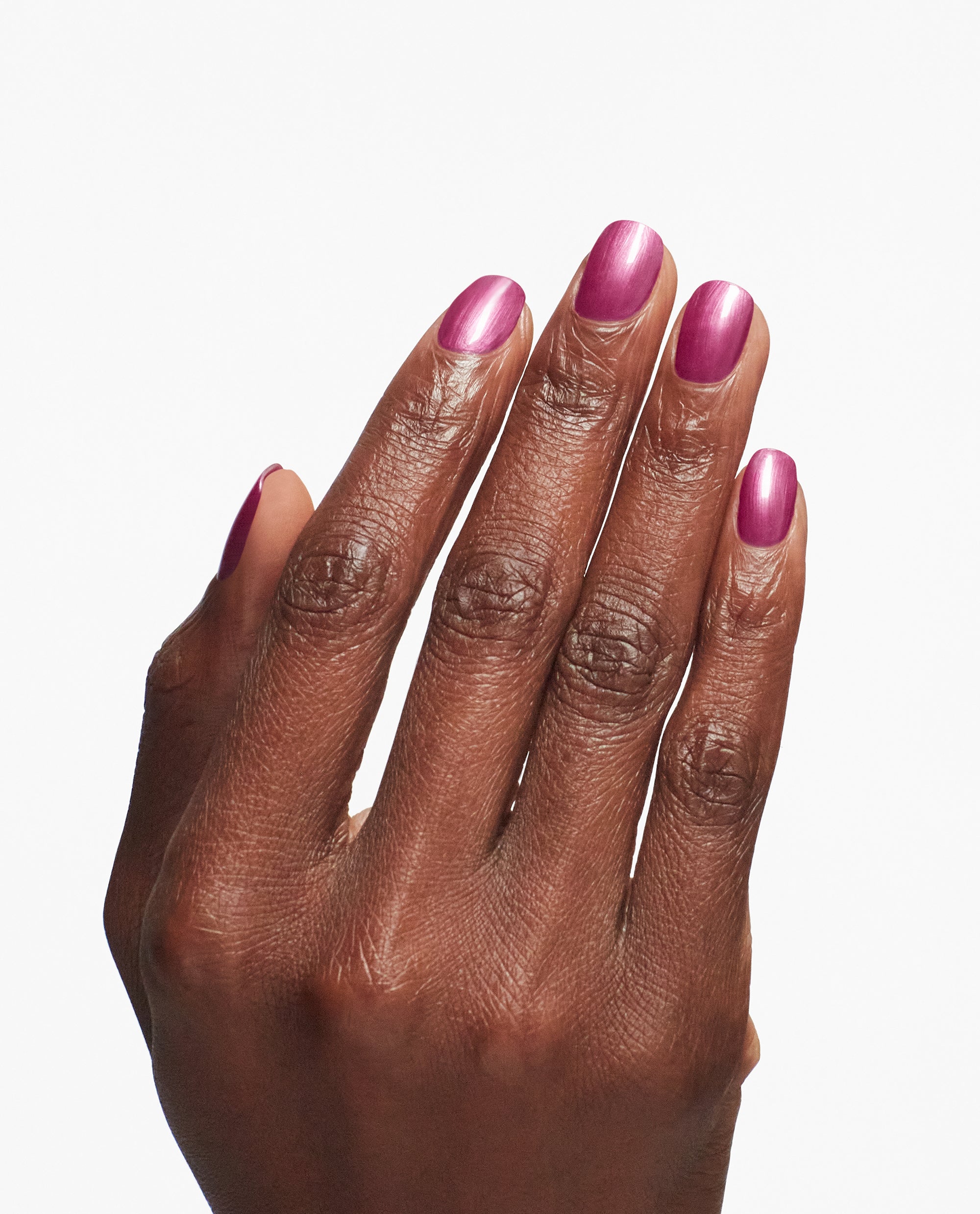 Hand displays a glossy metallic pink manicure using OPI Nail Envy Powerful Pink Nail Strengthener, a trending nail treatment, against a clean white background.