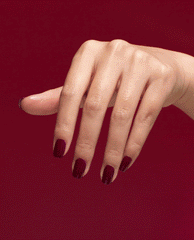 Hand shows glossy deep burgundy nails treated with OPI Nail Envy Tough Luv Nail Strengthener, a rich fall nail color, on a matching red background.