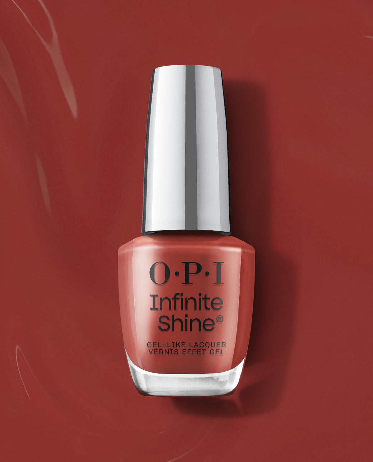 OPI Infinite Shine Nail Prep Rally gel-like lacquer bottle stands upright on a glossy terracotta red background, showcasing a warm coral shade for fall nail colors.