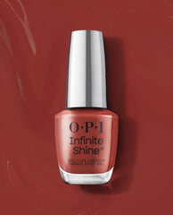 OPI Infinite Shine Nail Prep Rally gel-like lacquer bottle stands upright on a glossy terracotta red background, showcasing a warm coral shade for fall nail colors.