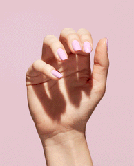 Hand displays glossy pastel mauve-pink nails painted with OPI Natural Mauvement Nature Strong vegan nail lacquer, a soft pick for fall nail colors, against a pale pink background.