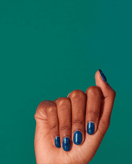Hand displays short, neatly manicured nails coated in Nessie Plays Hide & Sea-k, a shimmering deep teal-blue OPI nail polish, held against a solid teal background to showcase the glossy nail lacquer color and shine.