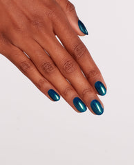 Hand with medium-length oval nails painted in OPI nail polish shade Nessie Plays Hide & Sea-k, a shimmery teal-blue nail lacquer with green reflects, shown against a clean white background to highlight the glossy finish.