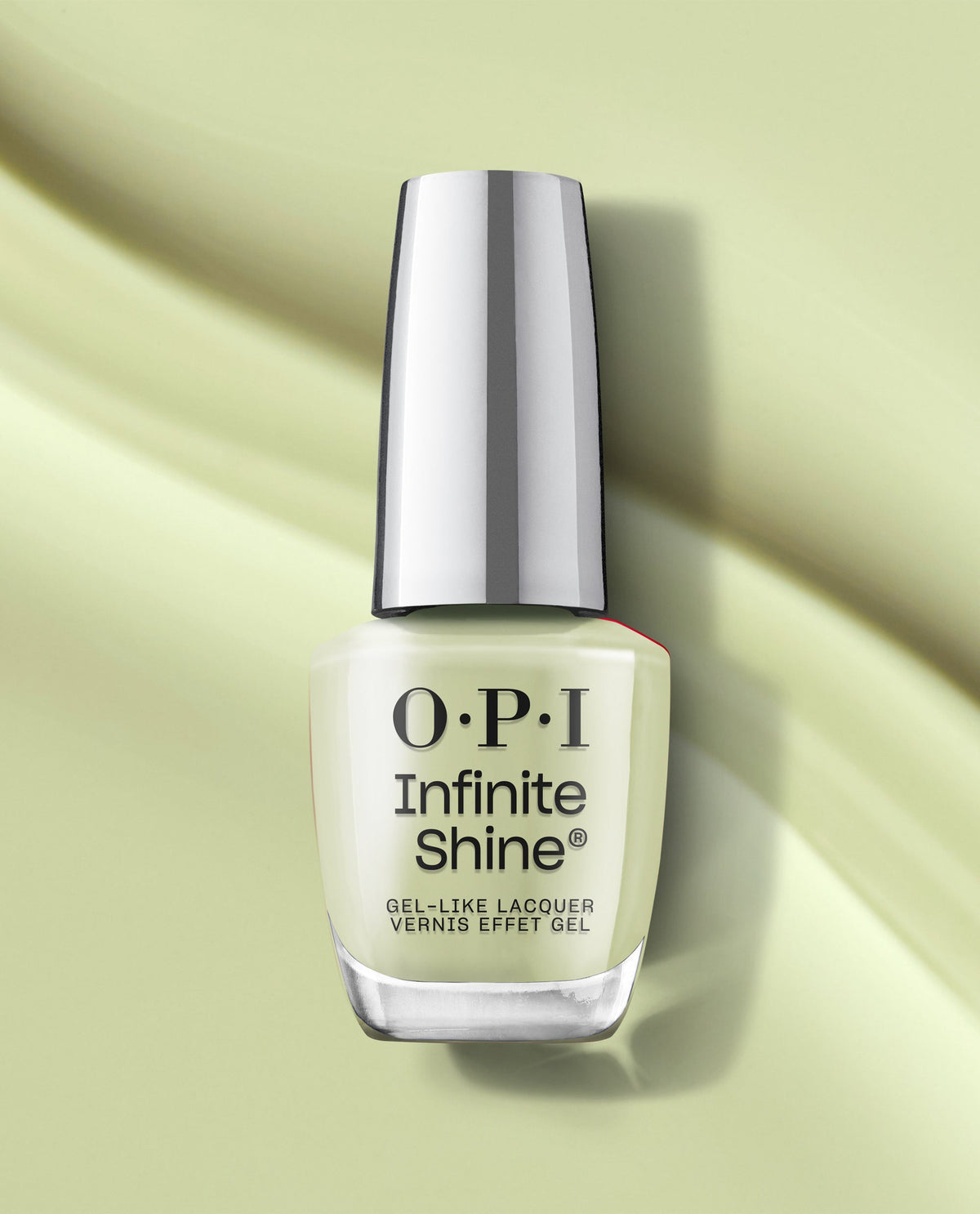 OPI Infinite Shine Oh Baby! gel-like nail lacquer bottle in a soft pastel yellow shade, standing upright on a light green surface with soft shadow accents.