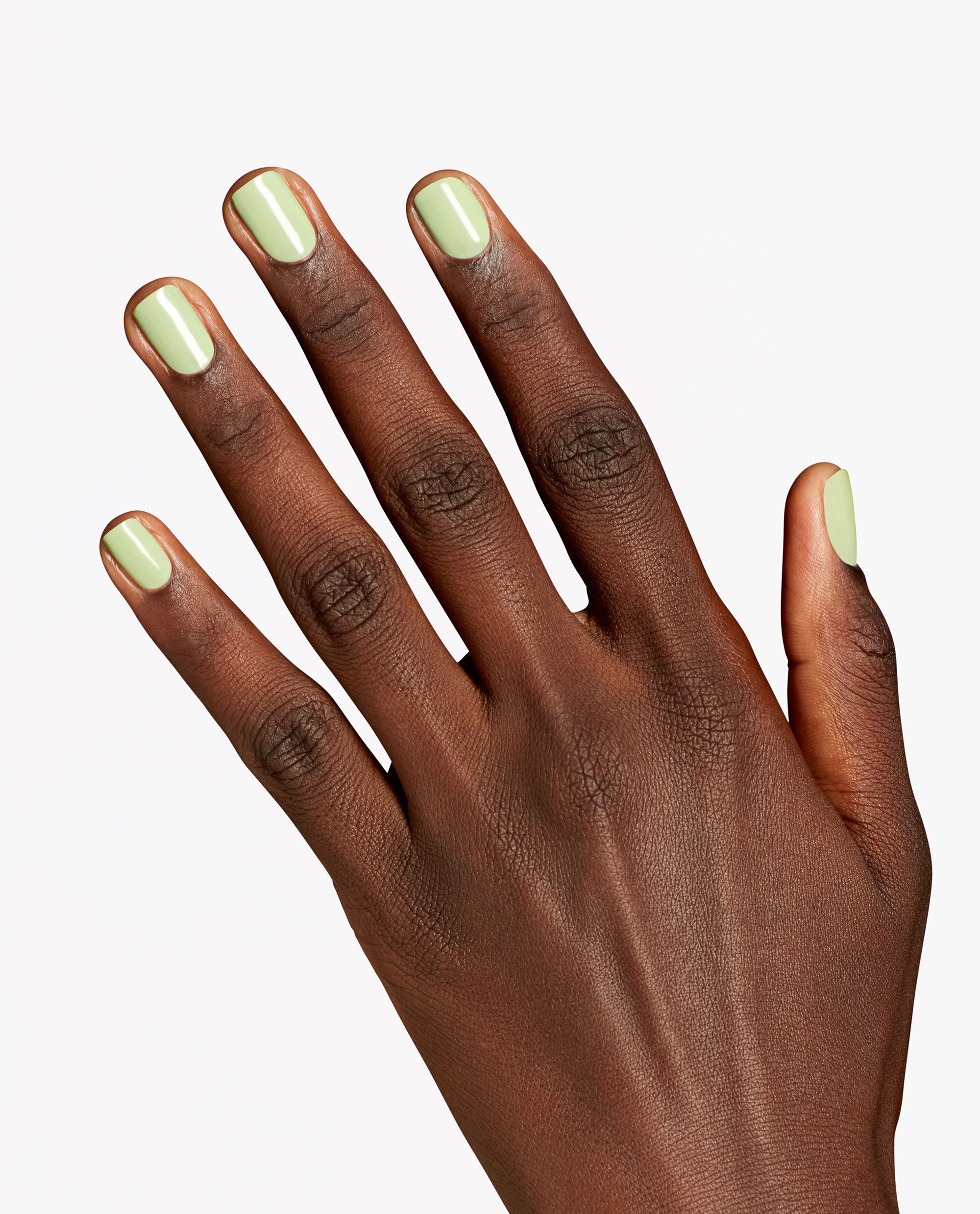 Hand displaying glossy pale green OPI Infinite Shine Oh Baby! nail polish on short rounded nails against a clean white background.