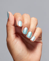 Hand with short, rounded nails painted in Pisces the Future OPI nail polish, a shimmery pastel aqua blue nail lacquer, shown against a plain light gray background to highlight the iridescent metallic finish.