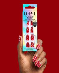 OPI Polka Dot Com Sticking Point press-on nails in glossy red with white polka dots, held on a manicured hand beside iridescent packaging against a red backdrop, a playful pick for fall nail colors.