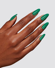 Almond-shaped nails flaunt a glossy pea-green manicure using Rated Pea-G Dipping Powder by OPI, a vibrant green nail polish ideal for spring nail colors, shown on a medium-brown hand against a clean light gray background.