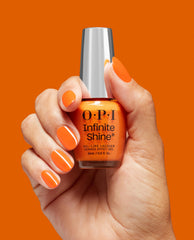 Hand with glossy orange manicure holds OPI nail polish Rollerbabe Infinite Shine bottle against a solid bright orange background, showcasing the vibrant long-wear gel-like finish for US nail lovers.