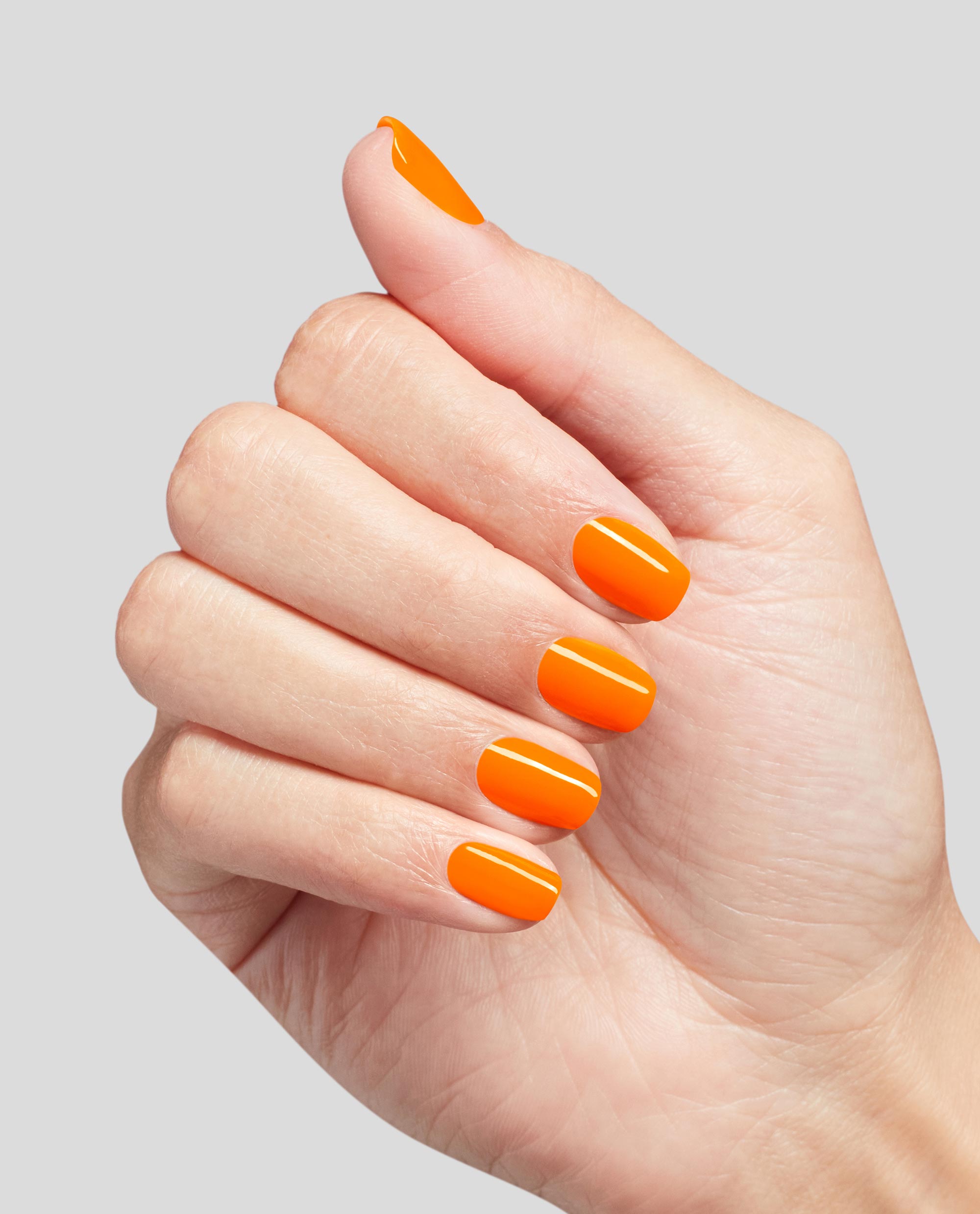 Hand shows short, neatly manicured nails painted in bright orange Rollerbabe Infinite Shine OPI nail polish, highlighting the glossy full-coverage finish against a clean light gray background.