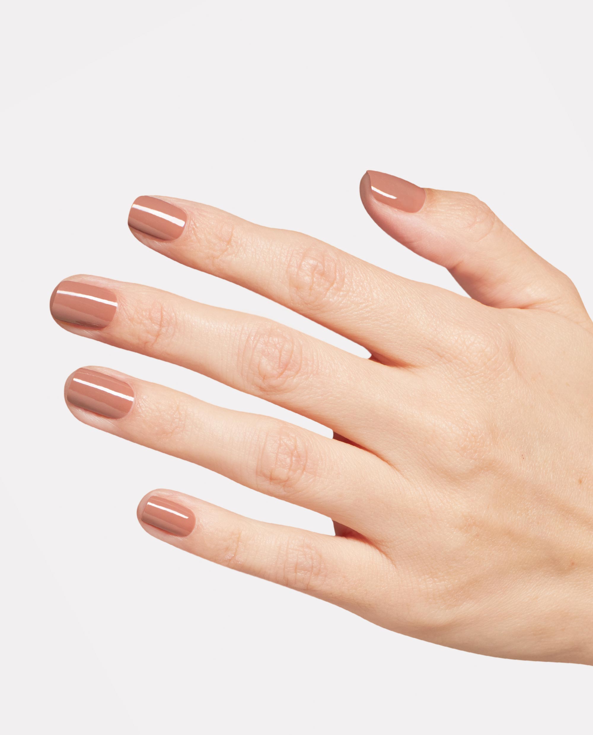 Hand displays glossy warm mauve-brown Rooting For Hue OPI Nature Strong Vegan Nail Lacquer on short rounded nails against a clean white background, a trending neutral manicure shade.