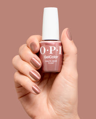 Hand holds OPI GelColor Route Beer Float gel nail polish in a shimmery rosy brown shade, with matching manicured nails against a mauve backdrop for fall nail colors.