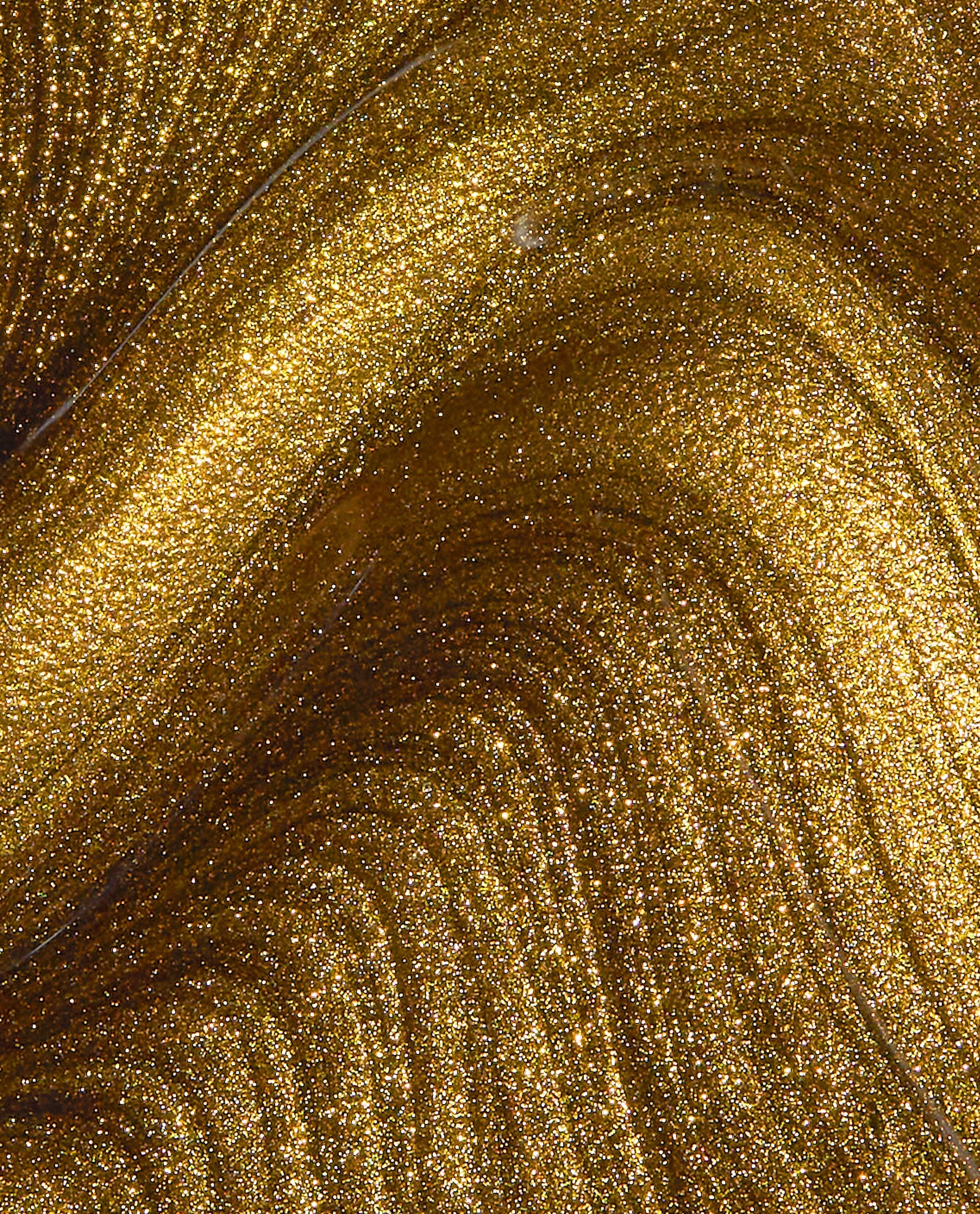 SaTURN Me On OPI nail polish nail lacquer swirling in close-up, showing dense metallic gold shimmer with fine glitter particles creating luminous, molten gold waves across the polish surface.