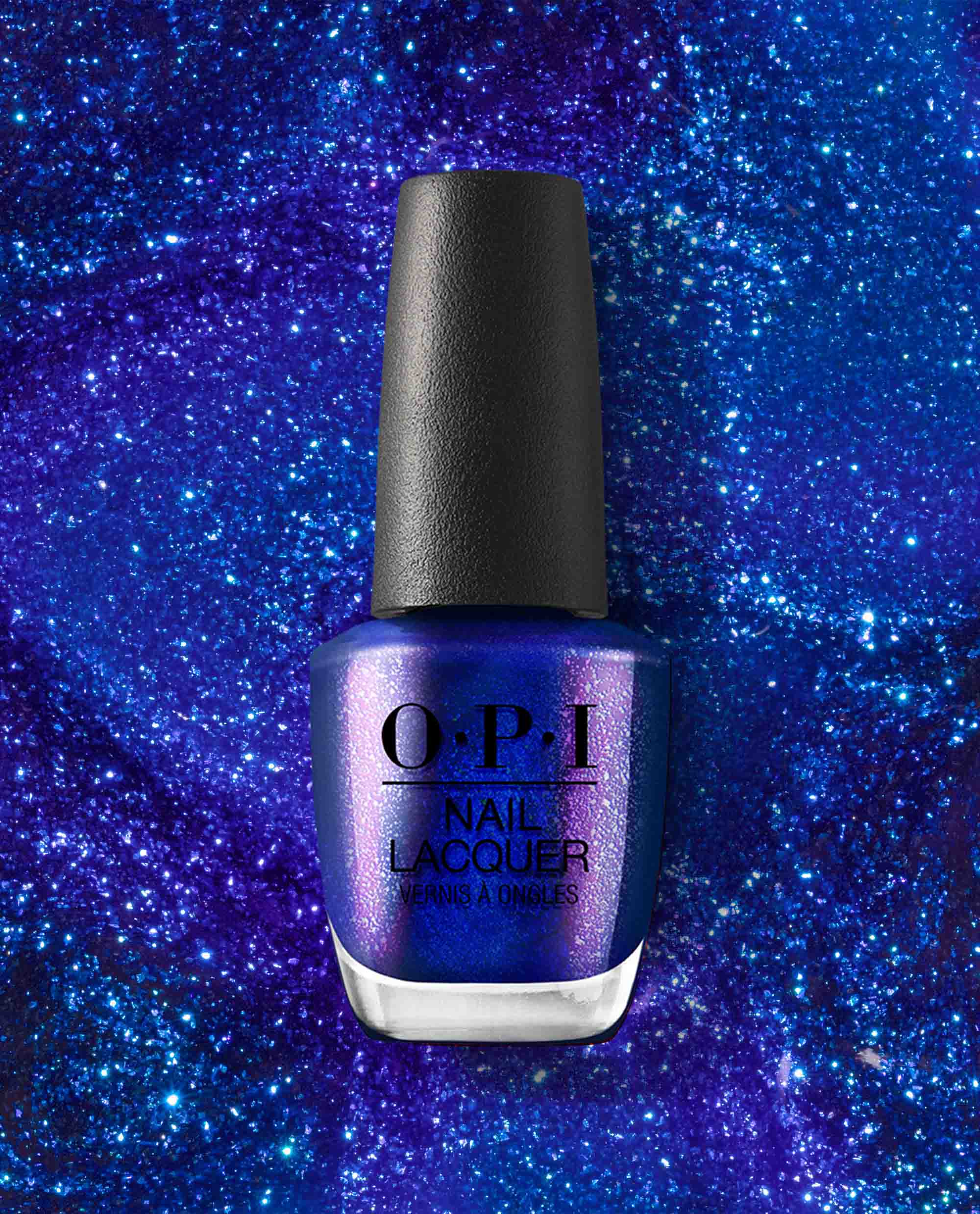 Scorpio Seduction OPI nail polish bottle displaying deep shimmery blue-purple nail lacquer, standing upright against a sparkling cosmic blue glitter background for a bold, celestial manicure look.