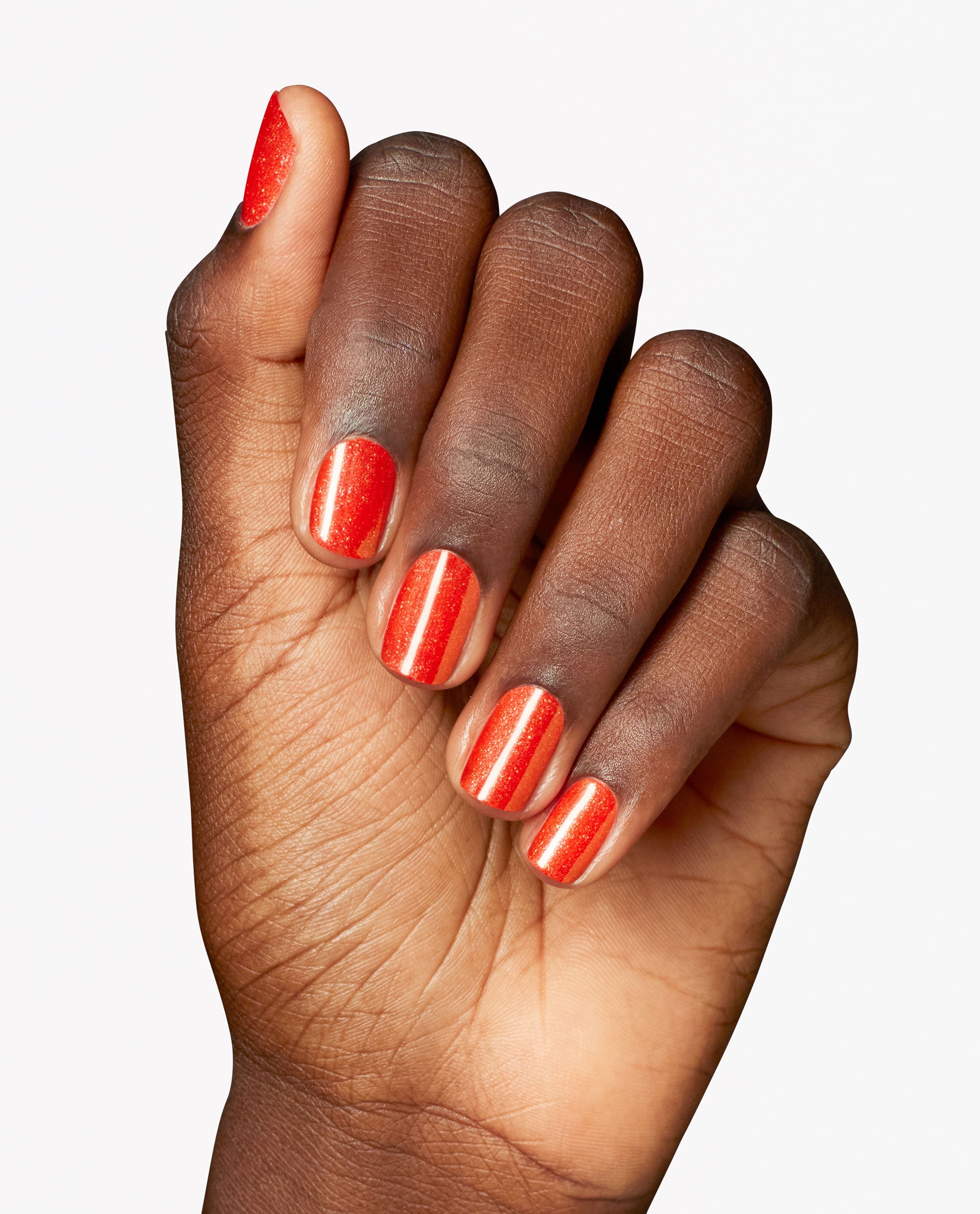 Hand displays glossy, shimmering orange nails painted with OPI Infinite Shine in Shock Em Orange, a trending bright manicure shade on a clean white background.