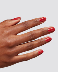 Hand with glossy red gel manicure showcasing OPI Single & Red-y at-home gel nail polish, a bold red shade for fall nail colors on a light gray background.