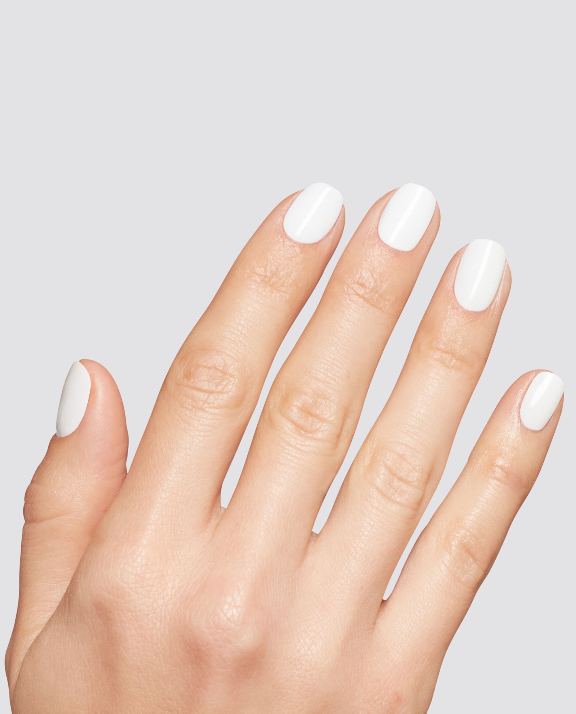 Hand with neatly manicured nails painted in Snow AnGEL opaque white at-home gel nail polish, shown against a light gray background to highlight glossy salon-quality coverage, ideal for OPI, nail polish gift set shoppers seeking crisp white nails.