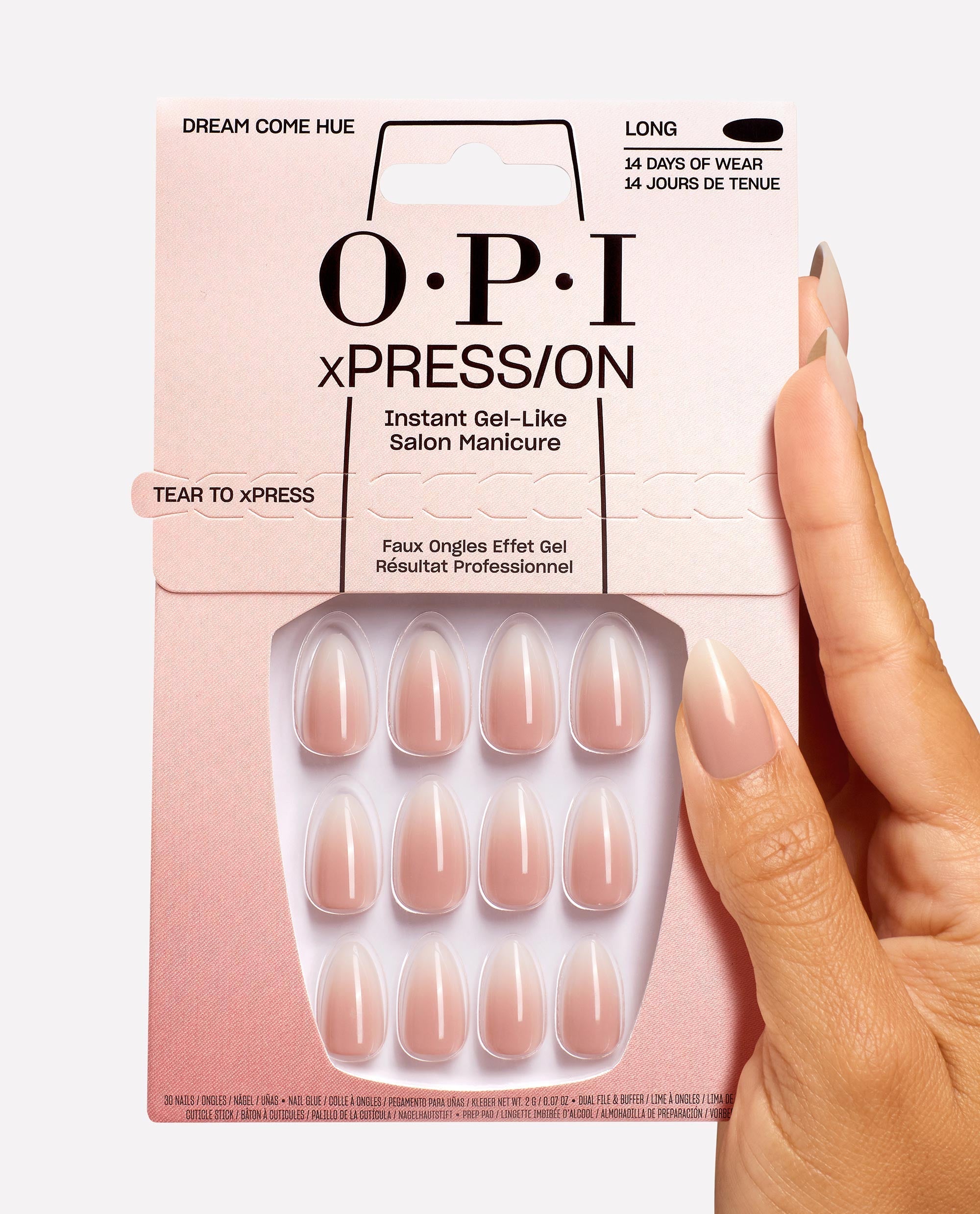 Hand with glossy nude press-on nails holds OPI Dream Come Hue xPRESS/ON Nail Art package, showcasing long, gel-like nude false nails in a pink box, ideal OPI nail polish gift set for salon-quality manicures at home.