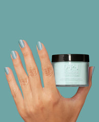 OPI Powder Perfection Reality Check Ya Out dipping powder, a green nail polish, shown on a manicured hand holding the jar, nails shimmering seafoam, perfect for spring nail colors against a matching teal background.