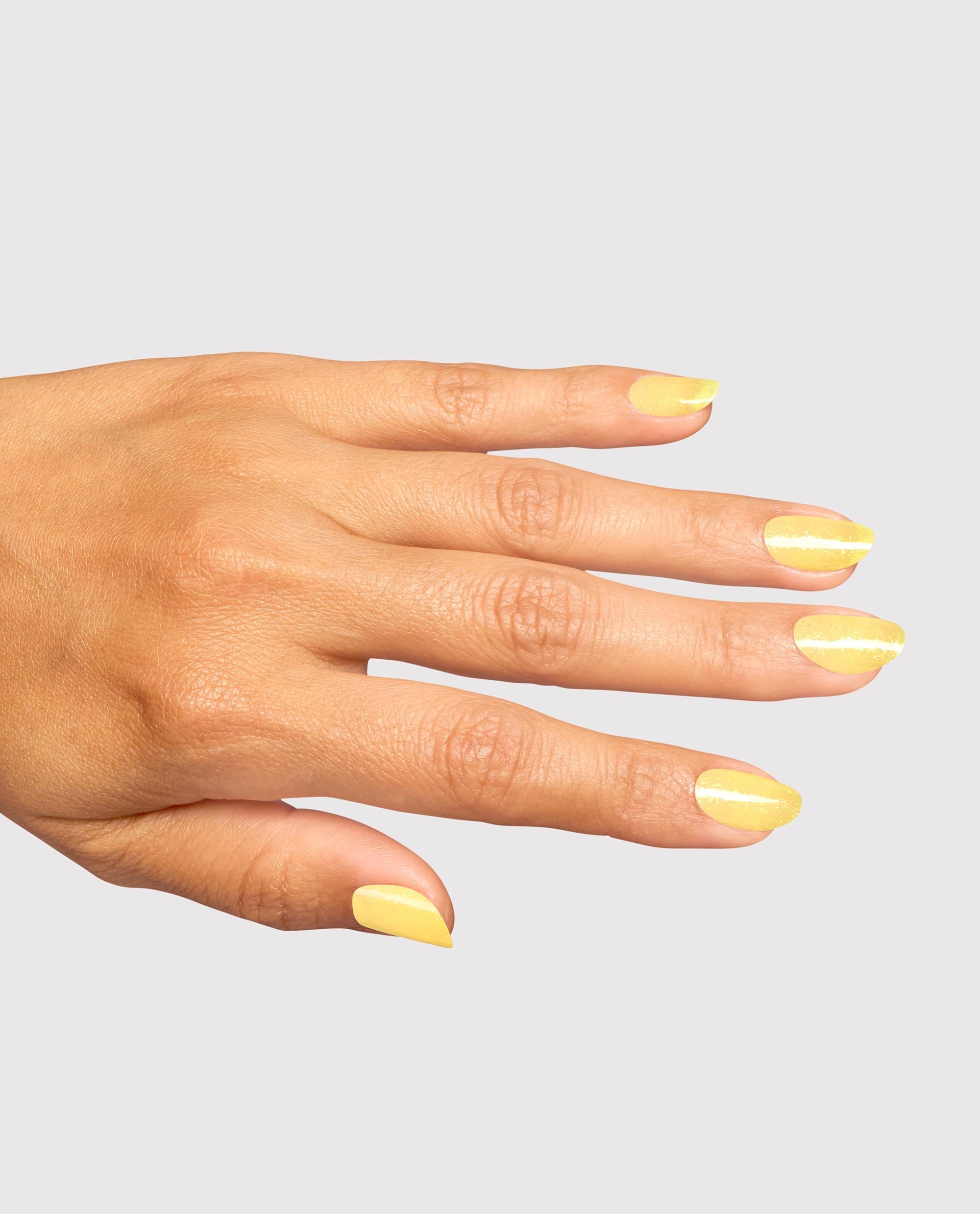 Hand modeling OPI Infinite Shine Slay Hello to Yellow, a glossy pale yellow nail polish with subtle shimmer on almond-shaped nails against a light gray background.