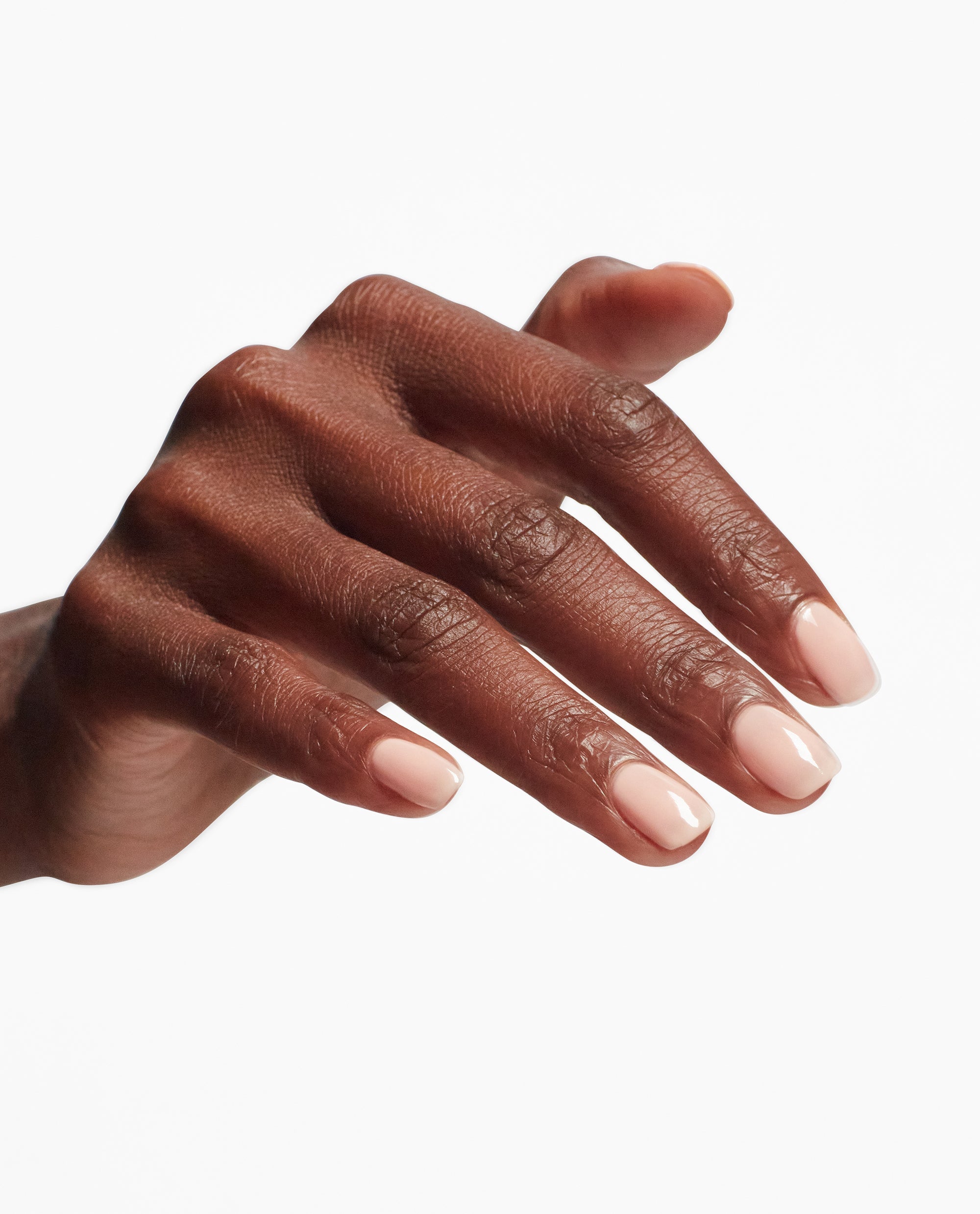 Hand with short, glossy nude nails showcases the smooth, high-shine finish created by OPI Start to Finish 3-in-1 Treatment top and base coat, ideal as a nail polish gift set against a clean white background.