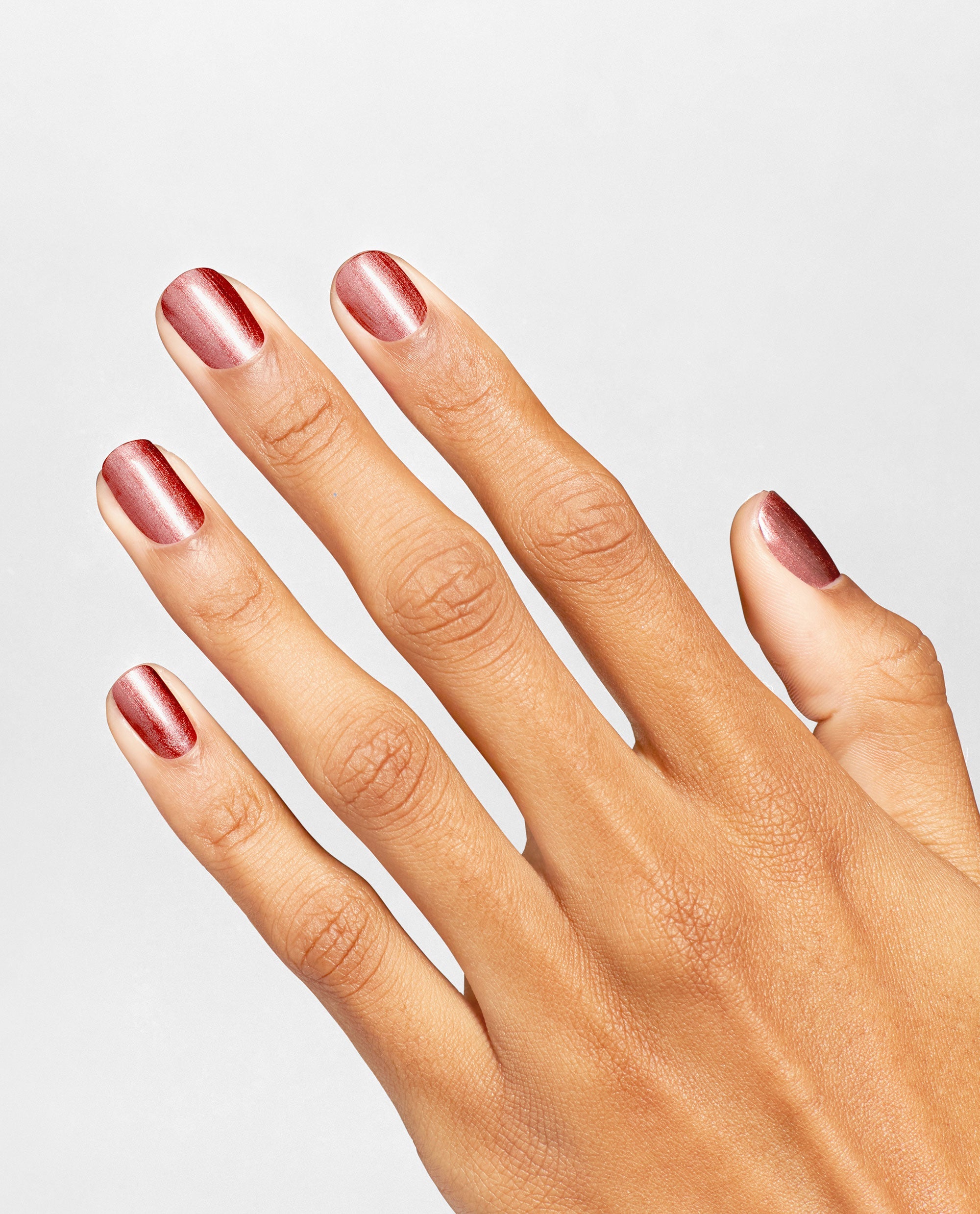 Hand displays manicured nails painted with OPI nail polish Stellar Tips Infinite Shine, showing a metallic rose-red shimmer finish against a clean light gray background for a modern, salon-quality look.