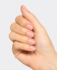 Hand displaying glossy soft pink OPI Infinite Shine nails in Still Going Strong, a polished manicure shade for fall nail colors on a clean white background.