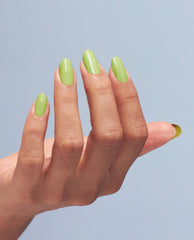 Manicured hand showcasing OPI Summer Monday-Fridays Nail Lacquer, a glossy light green nail polish, nails oval and neatly filed, fingers posed against a soft blue backdrop, spotlighting fresh spring nail colors for weekday wear.
