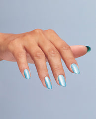 Hand model showing Surf Naked nail lacquer manicure in shimmering icy blue on short almond nails against a pale blue background, a trending nail colors look inspired by OPI shades.