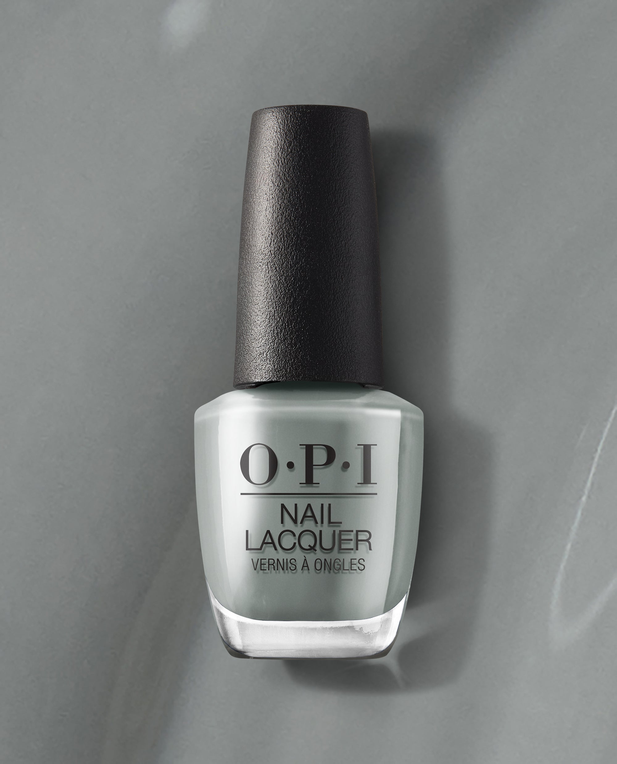 OPI nail polish bottle of Suzi Talks with Her Hands nail lacquer standing upright, showcasing its cool gray shade and black cap against a matching gray background for a modern, minimalist product display.
