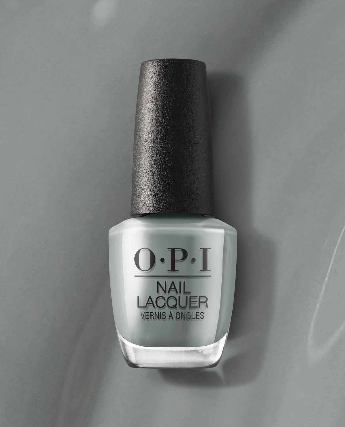 OPI nail polish bottle of Suzi Talks with Her Hands nail lacquer standing upright, showcasing its cool gray shade and black cap against a matching gray background for a modern, minimalist product display.