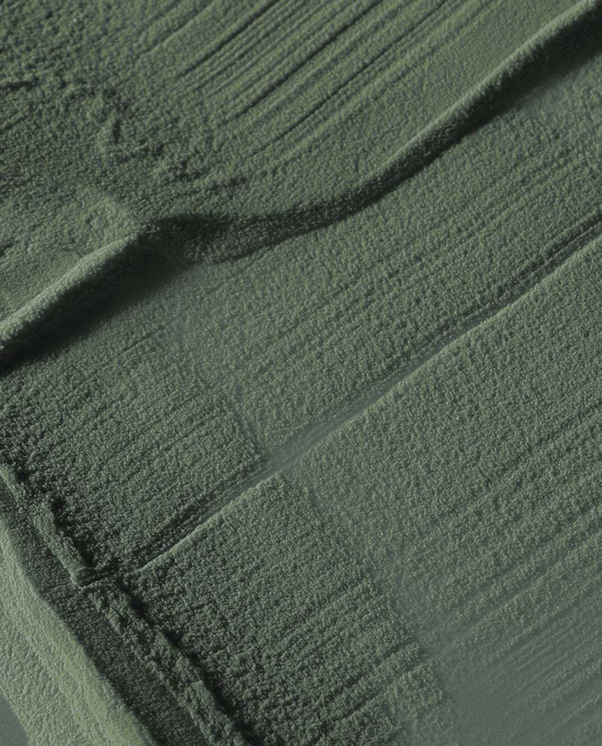 Suzi - The First Lady of Nails dipping powder swatch spreading in velvety, brush-textured strokes across a flat surface, showcasing an olive green nail polish shade for spring nail colors by OPI.