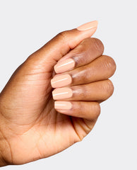 Hand modeling glossy peach-nude OPI Suzi Take a Vow Nail Lacquer on short square nails, showcasing a soft neutral shade for fall nail colors against a light gray background.