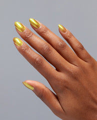 Hand with medium-dark skin tone showing long almond-shaped nails painted in The Leo-nly One metallic yellow-gold OPI nail polish, displayed against a plain gray background to highlight the shimmering nail lacquer finish.