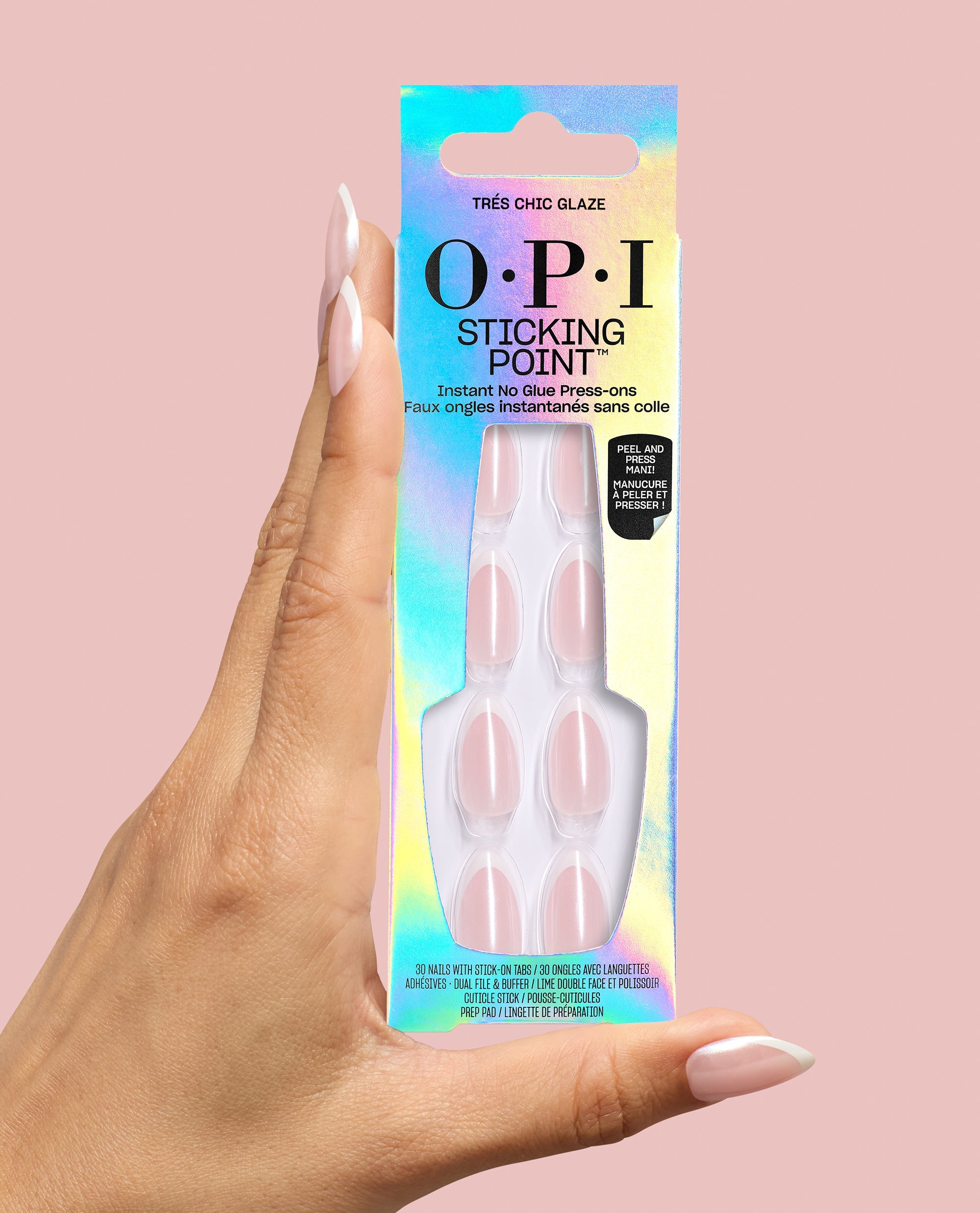 Hand holding OPI Sticking Point Très Chic Glaze no-glue press-on nails in an iridescent box, showing pale pink almond French tips against a soft pink background, ideal for fall nail colors.