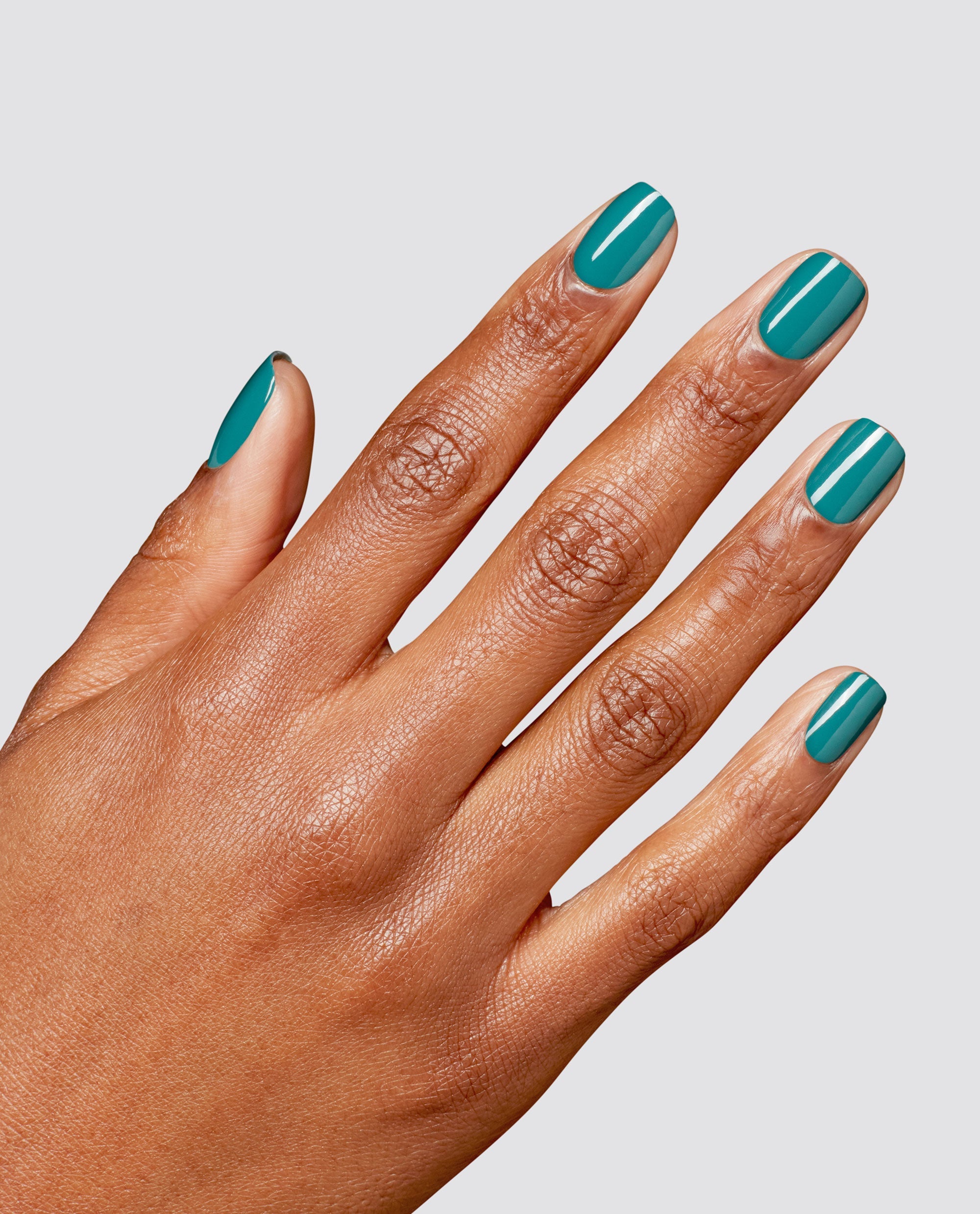 Hand with medium-brown skin tone shows neatly manicured nails painted in glossy teal from the What a Winterful World OPI RapiDry nail polish gift set against a clean light gray background.