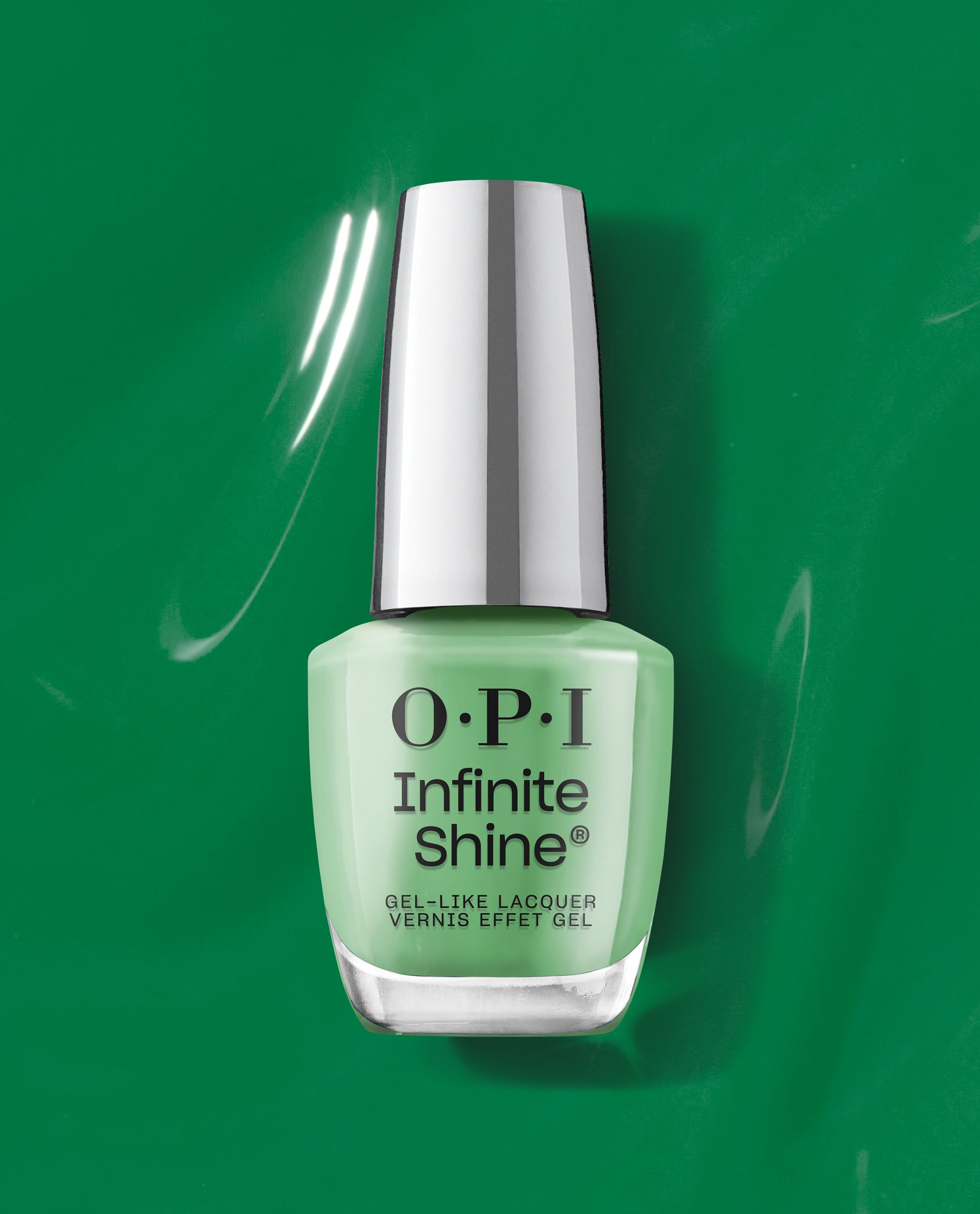 OPI Infinite Shine Won for the Ages bottle standing against a glossy green backdrop, mint green nail polish glowing with light reflections beneath a silver cap, showcasing long-lasting gel-like shine for spring nail colors and OPI green nail polish.